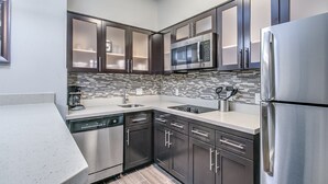 A modern kitchen with stainless steel appliances, dark cabinets, and a tiled backsplash. - Staybridge Suites Lubbock South by IHG (Lubbock)