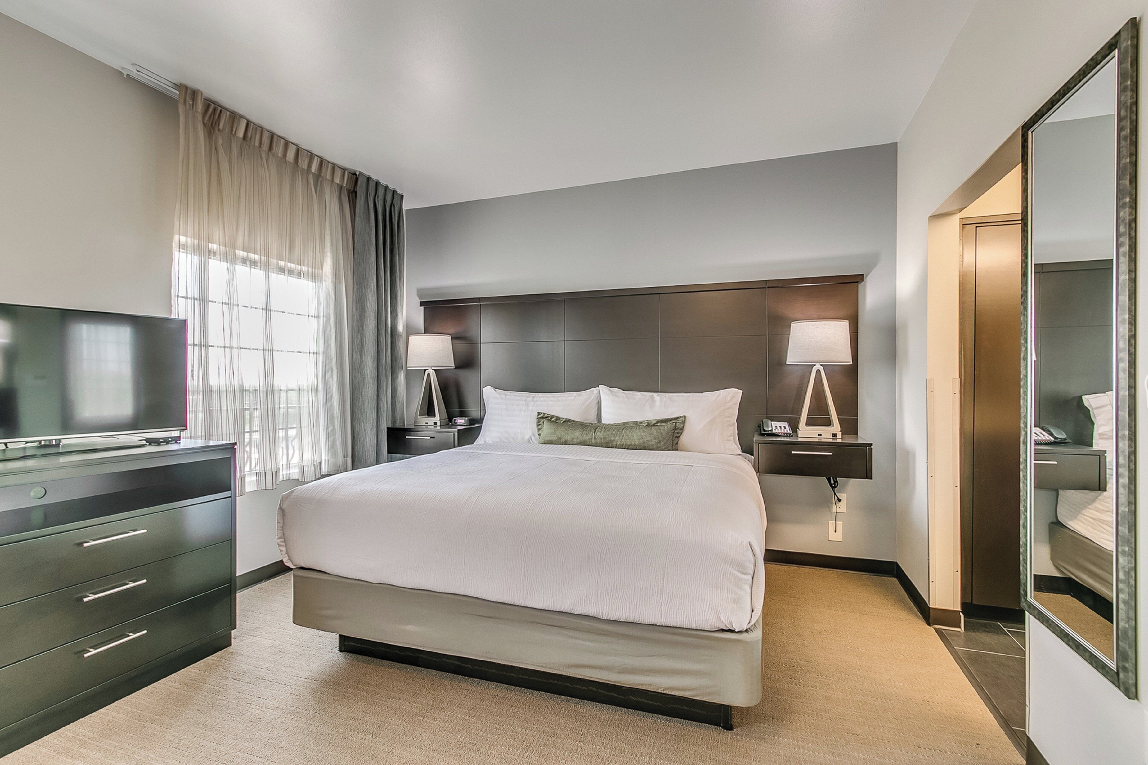 A hotel room with a large bed, bedside lamps, a television, and a wardrobe.