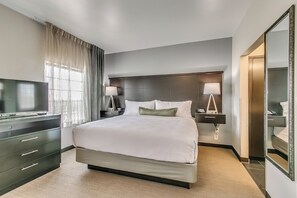 Ein Hotelzimmer mit einem großen Bett, Nachttischlampen, einem Fernseher und einem Kleiderschrank.