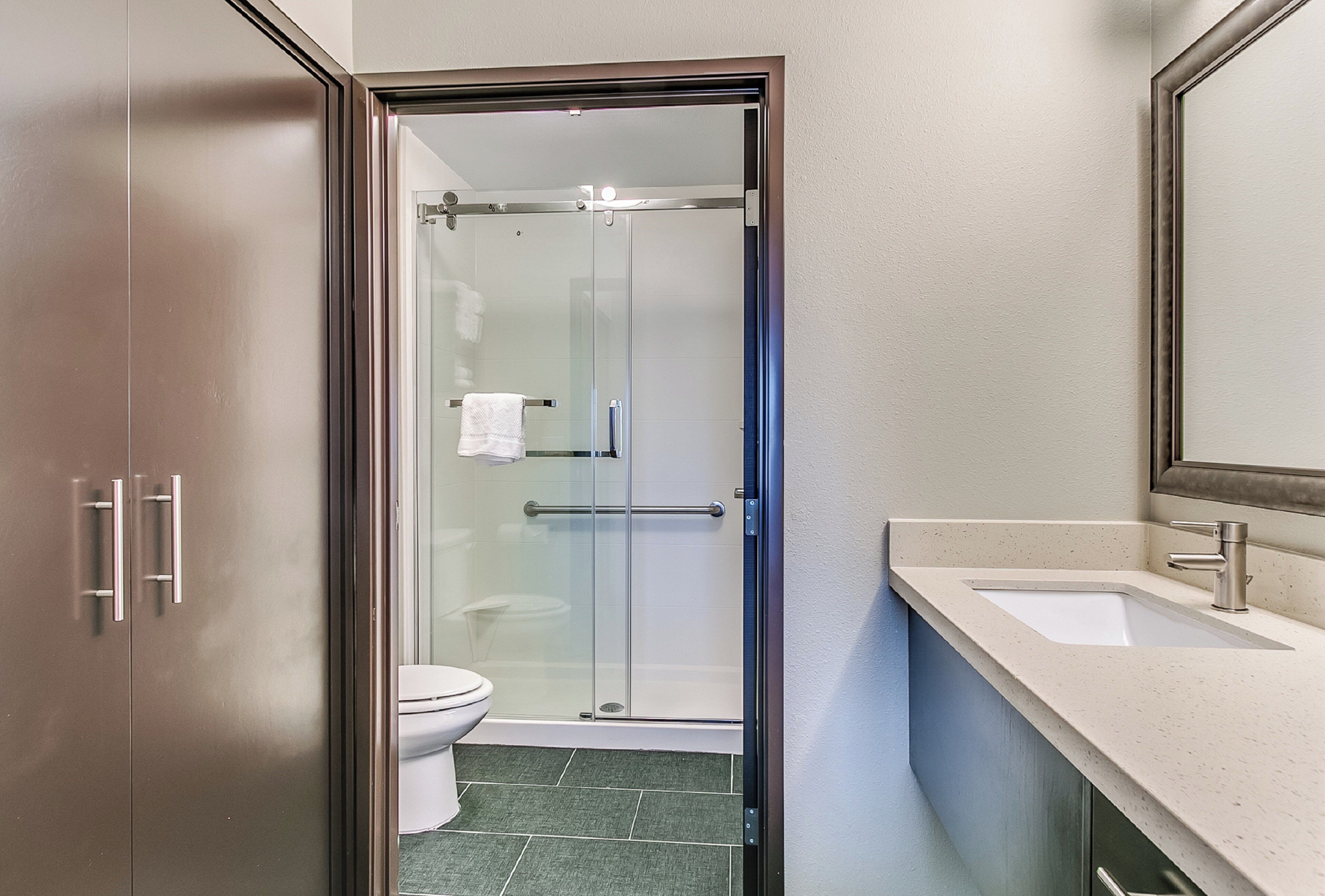 A modern bathroom with a glass shower enclosure, a toilet, and a sink with a mirror above it.