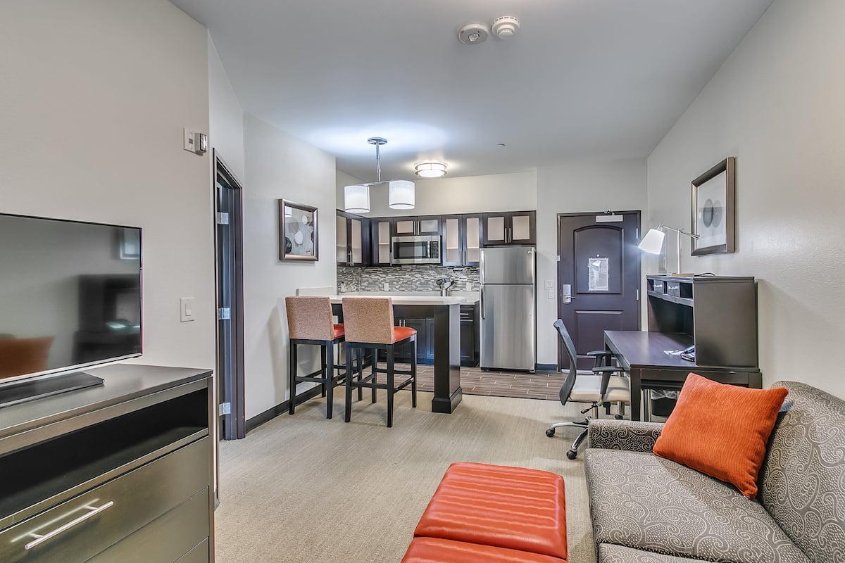 A compact living space with a kitchenette, a dining area, and a seating area with a sofa and ottoman.