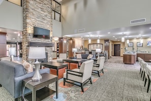A hotel lobby with a stone accent wall, a flat-screen TV, and a fireplace. - Staybridge Suites Lubbock South by IHG (Lubbock)