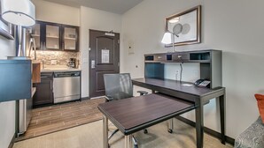 A compact kitchen with modern appliances, a dining area with a table and chairs, and a small office space with a desk and phone. - Staybridge Suites Lubbock South by IHG (Lubbock)