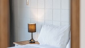 A hotel room with a neatly made bed, a bedside lamp, and a painting on the wall. - Roselands Motel (Tauranga)