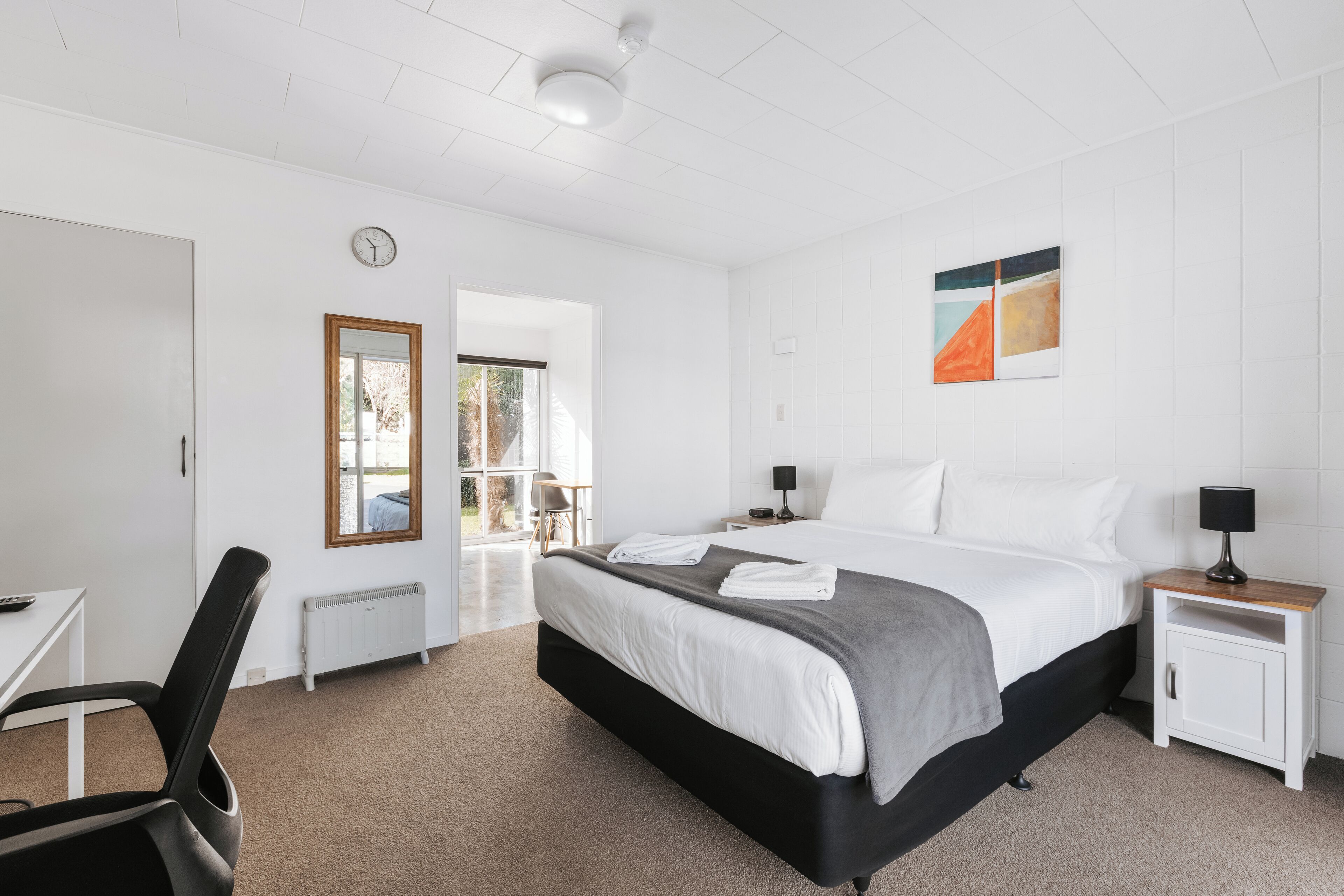 Een moderne hotelkamer met een groot bed, nachtkastjes, een bureau en uitzicht op de omgeving.