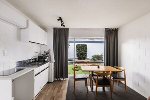 Una cocina compacta con comedor, vista a un jardín y pared de ladrillo blanco.