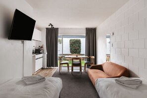 Un espacio habitable compacto con kitchenette, televisor de pantalla plana, zona de comedor y sofá.