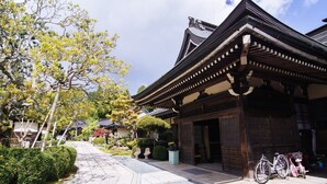 A traditional Japanese building with a tiled roof and wooden beams. There are bicycles parked in front and a gravel path leading to the entrance. - Jokiin (Koya)