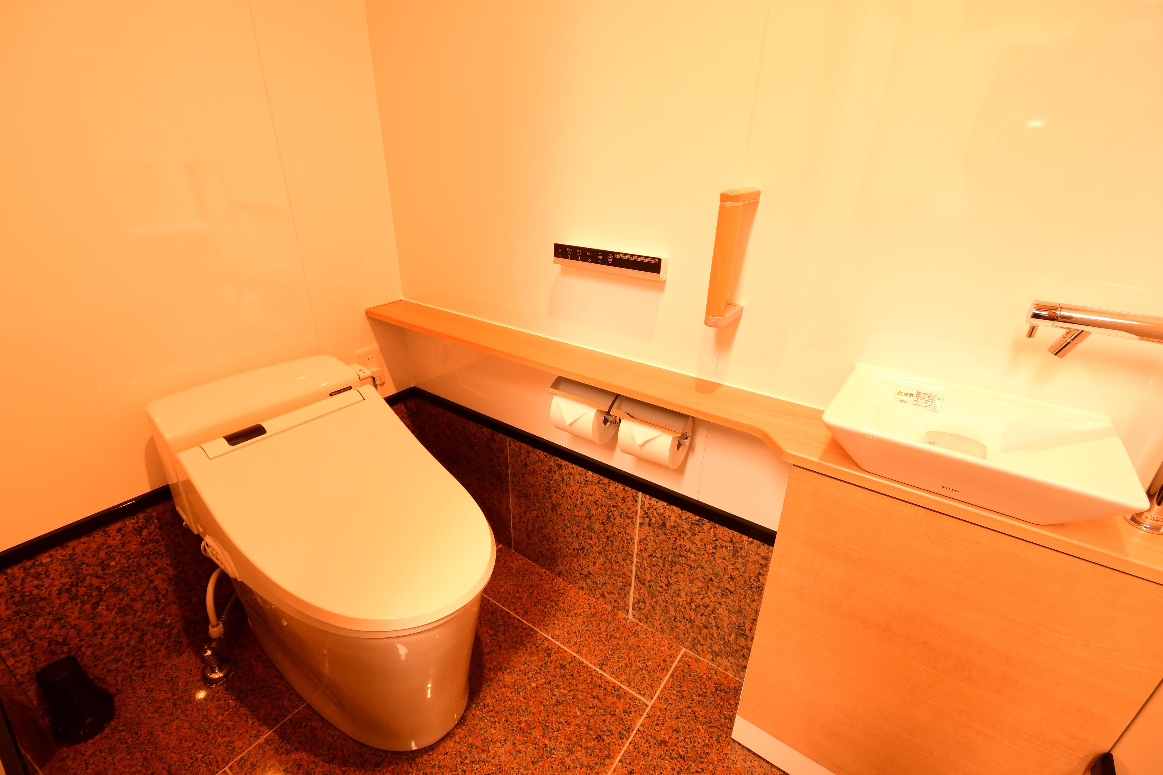 Une salle de bain équipée de toilettes, d’un lavabo et d’un distributeur d’essuie-tout.