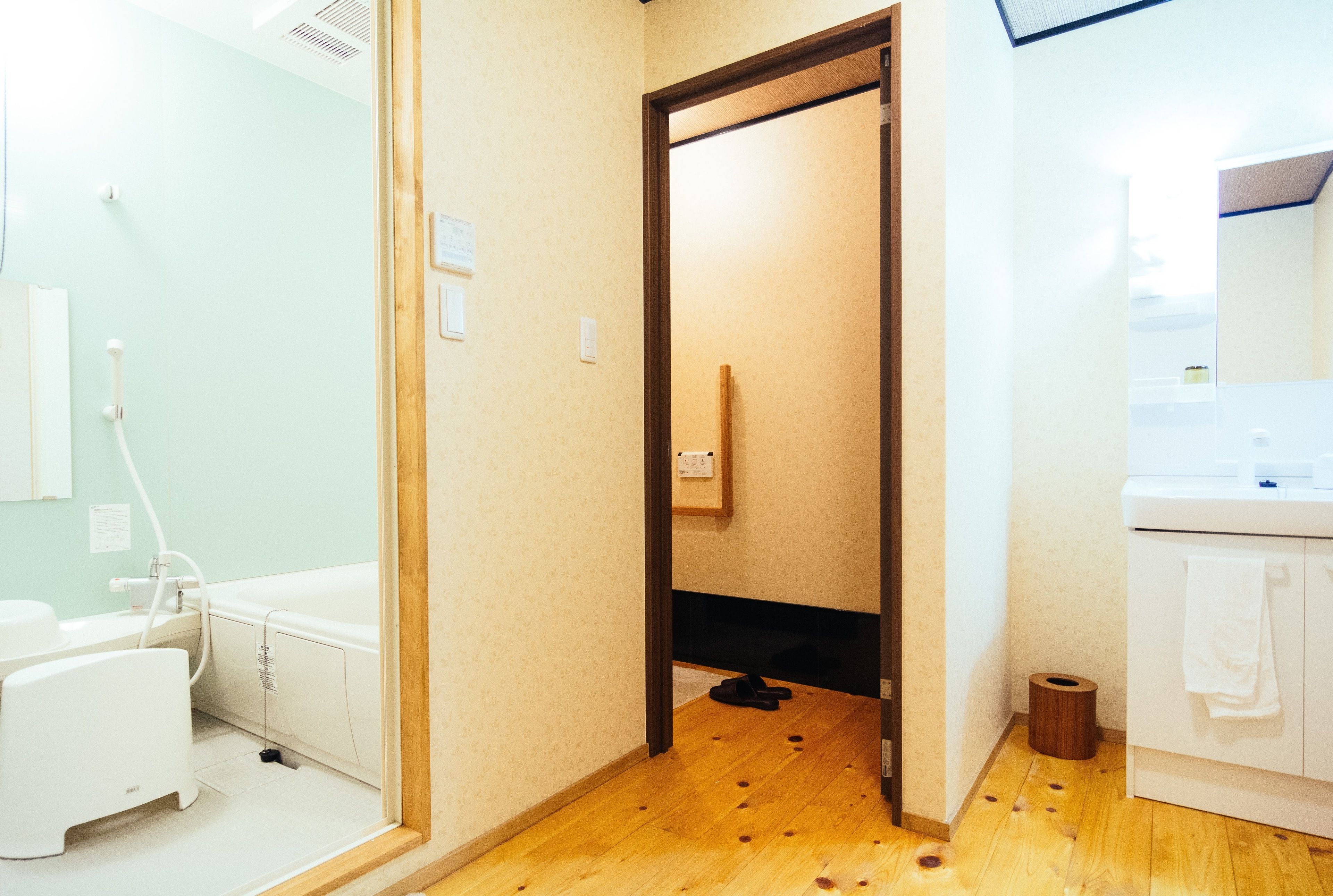 A bathroom with a wooden floor, a white sink, and a toilet.