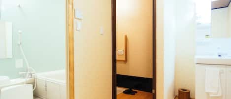 A bathroom with a wooden floor, a white sink, and a toilet.