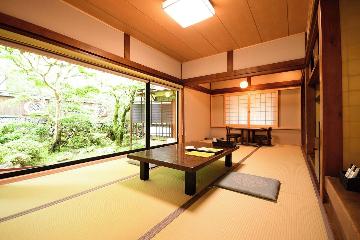 A tatami mat room with a low table, sliding doors, and a view of a garden.