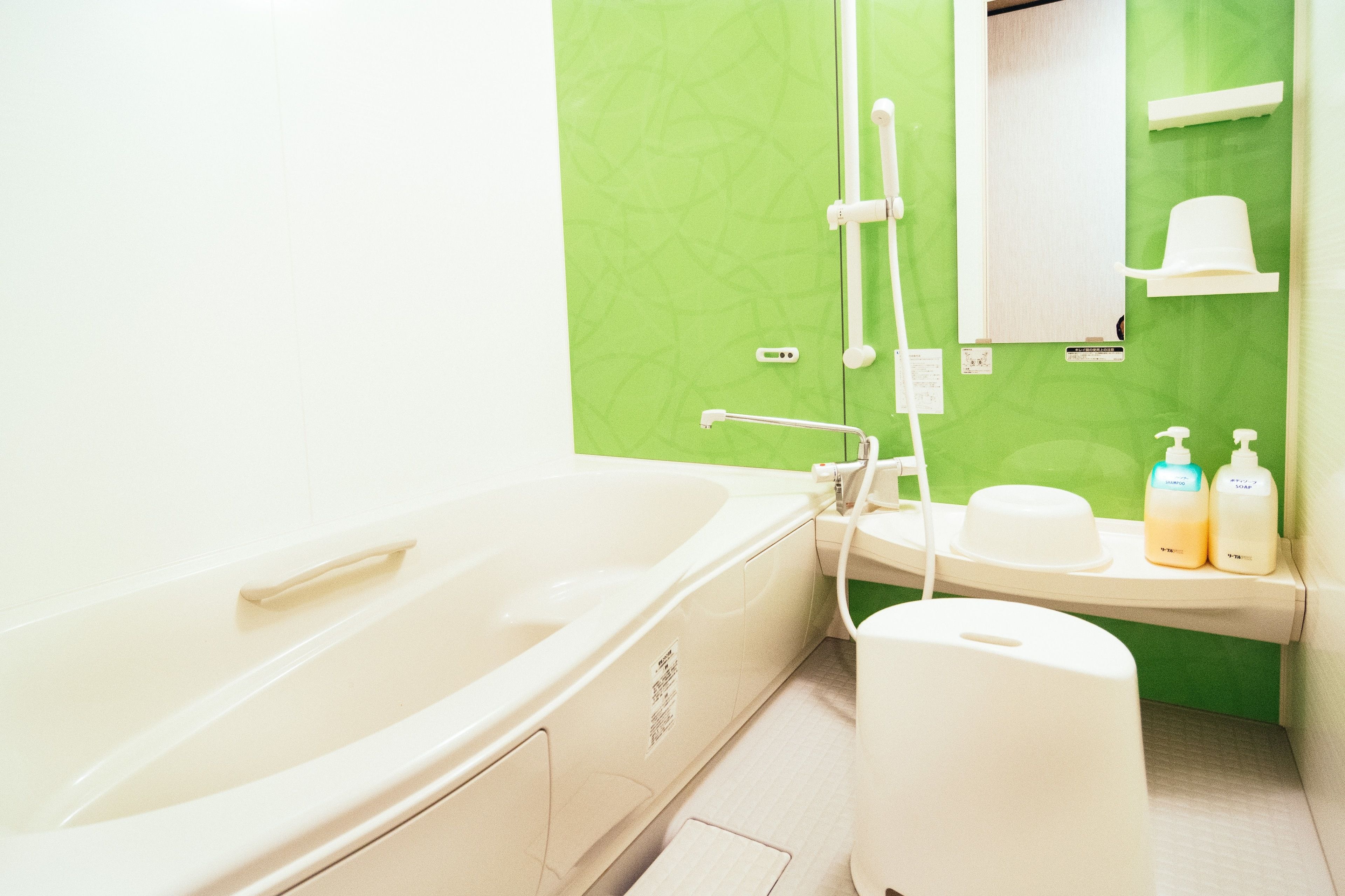 A bathroom with a bathtub, sink, and toilet. There are toiletries on the sink counter.