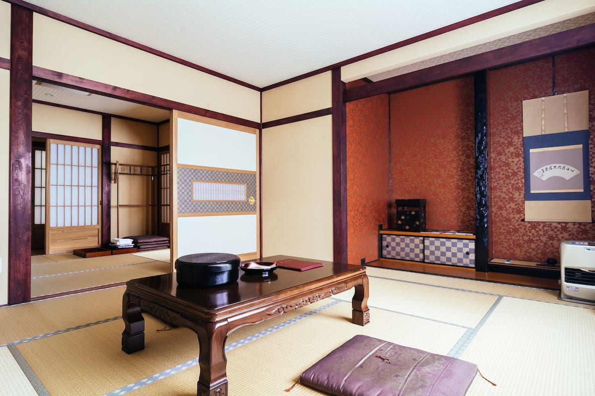 A traditional Japanese room with tatami flooring, a low wooden table, and a sliding door.