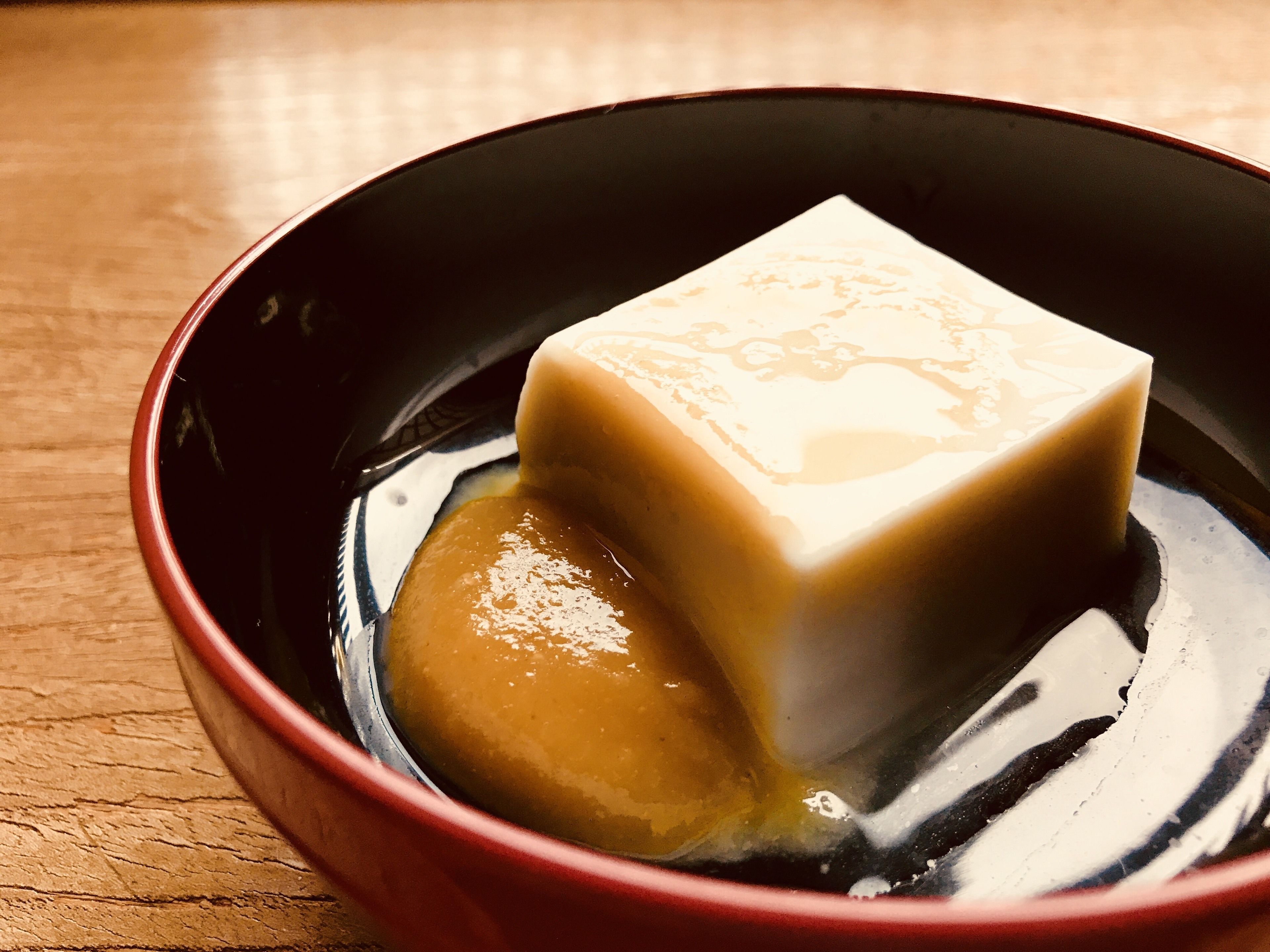 A bowl with a cube of tofu and a liquid.