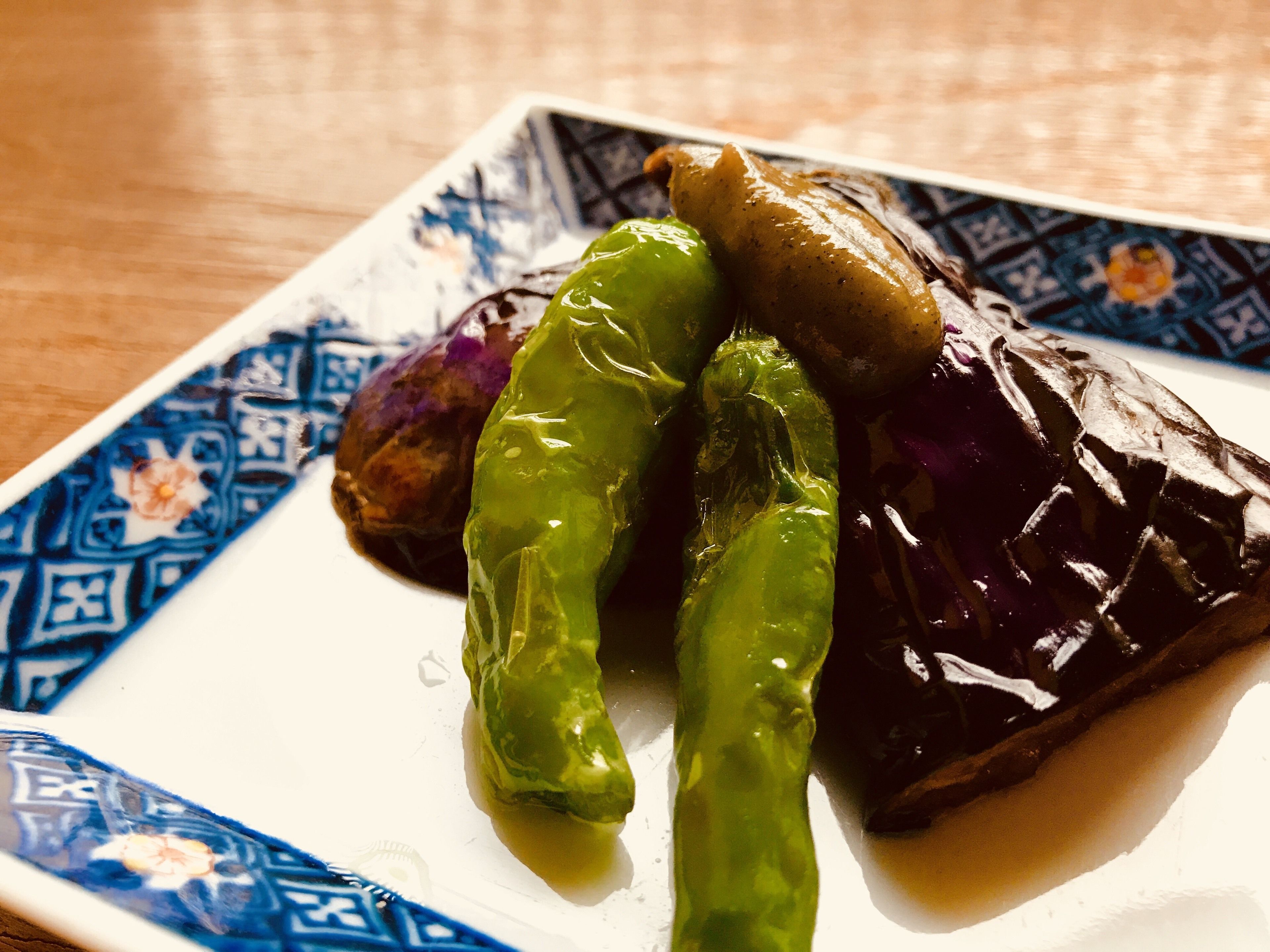 Ein Teller mit gefüllten Paprika und einem violetten Gemüse, vermutlich Auberginen, auf einem gemusterten Teller.