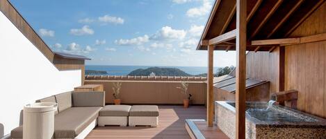 A wooden deck with a seating area, a hot tub, and a view of the ocean.