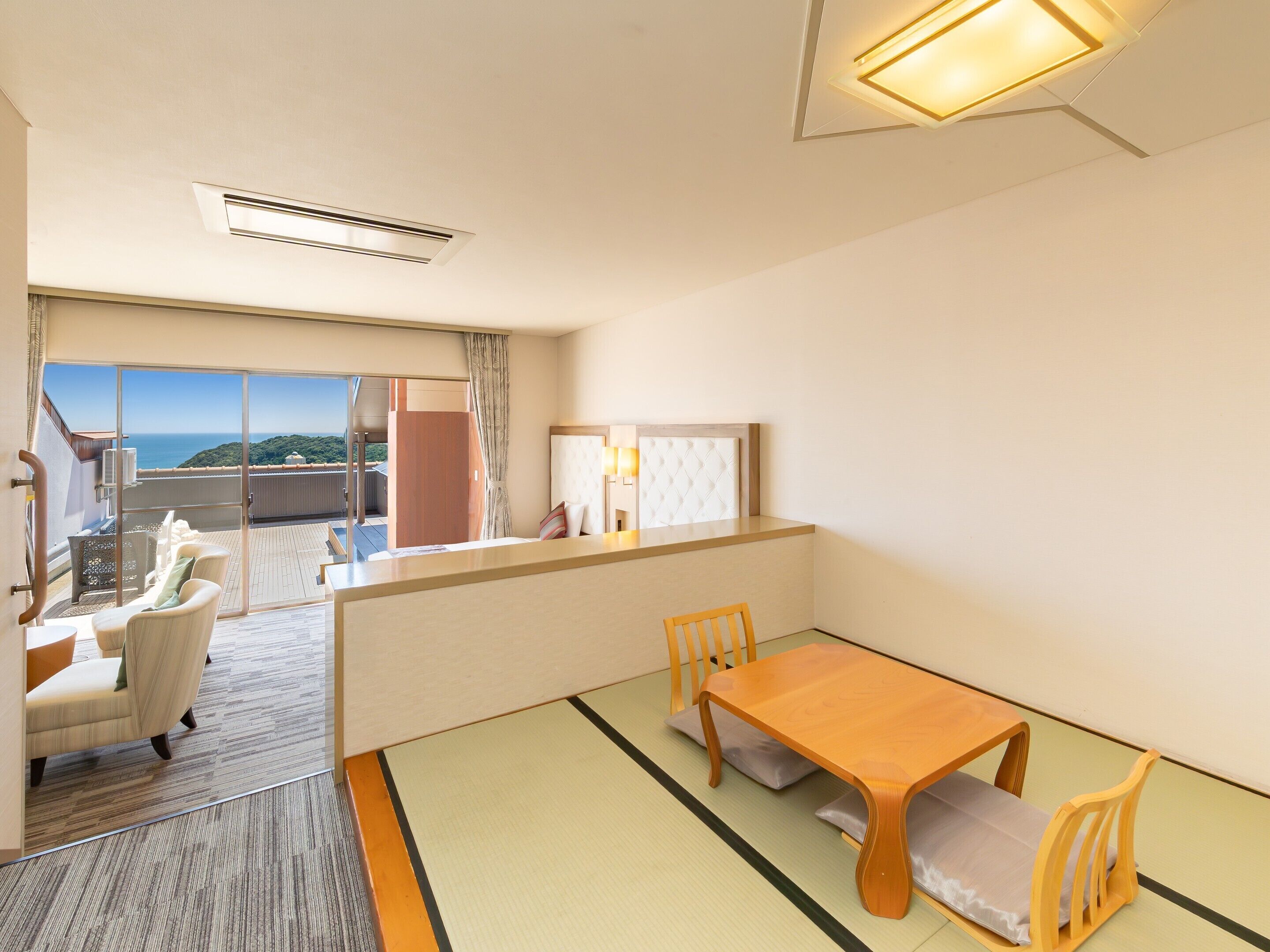 A hotel room with a sliding glass door leading to a balcony with a view of the sea.
