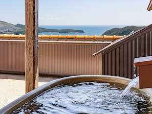 Un élément décoratif aquatique sur un balcon offrant une vue sur l’océan et les collines.