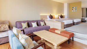 Een hotelkamer met een bank, een houten tafel, een bed en een kleine tafel met stoelen.