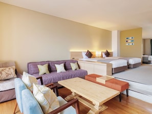Habitación de hotel con sofá, una mesa de madera, cama y una pequeña mesa con sillas.