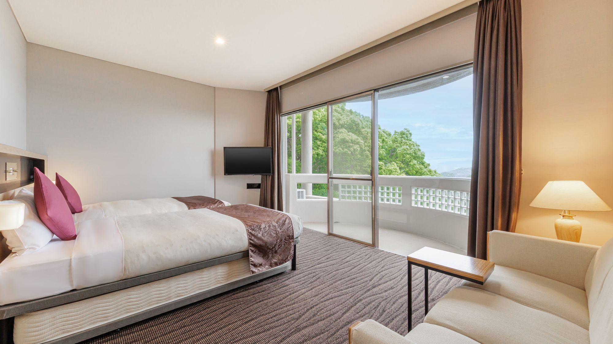 Une chambre d’hôtel avec un lit, une télévision, un balcon et un canapé.