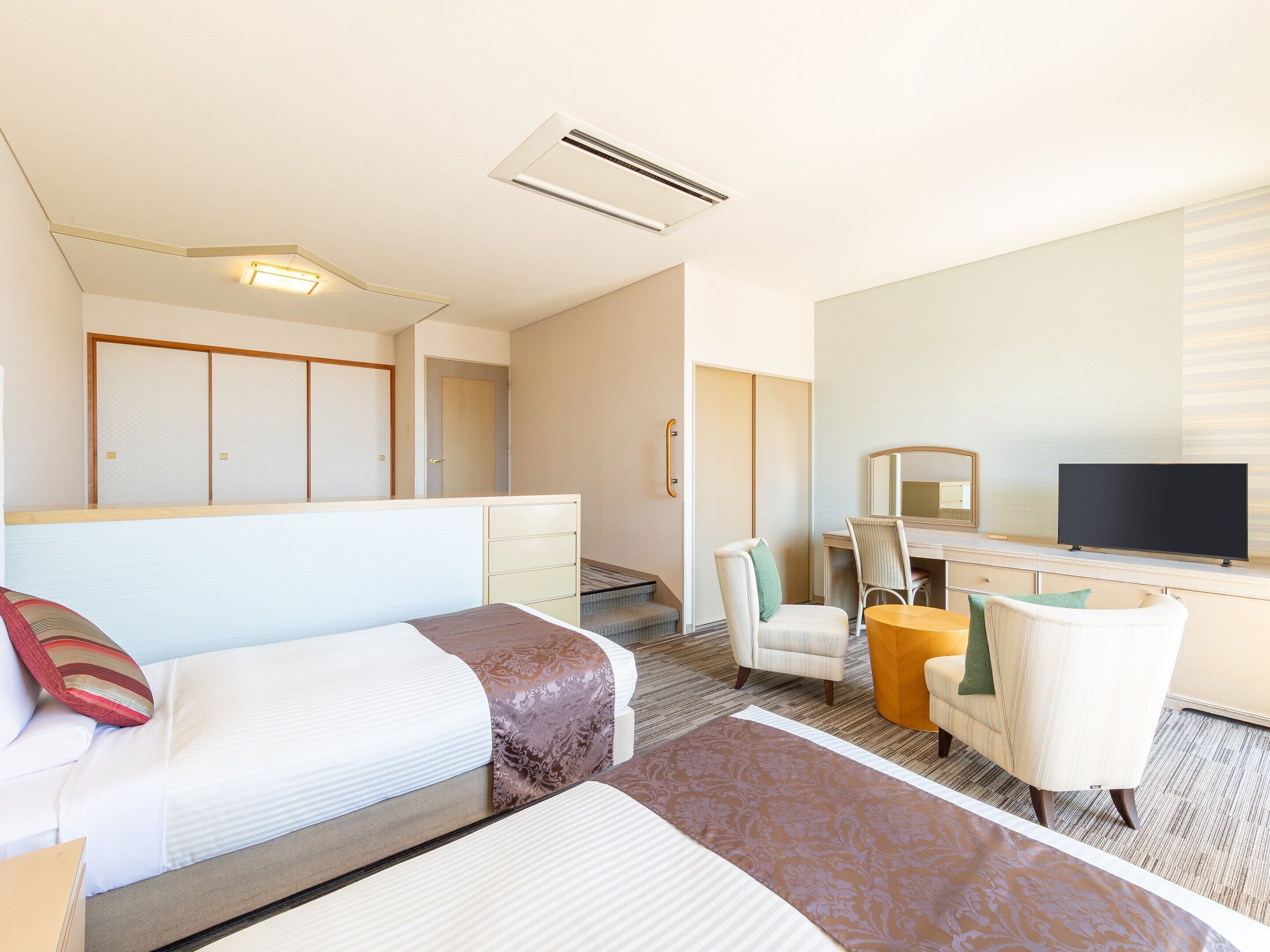 A hotel room with a bed, a desk, a chair, a television, and a wardrobe.
