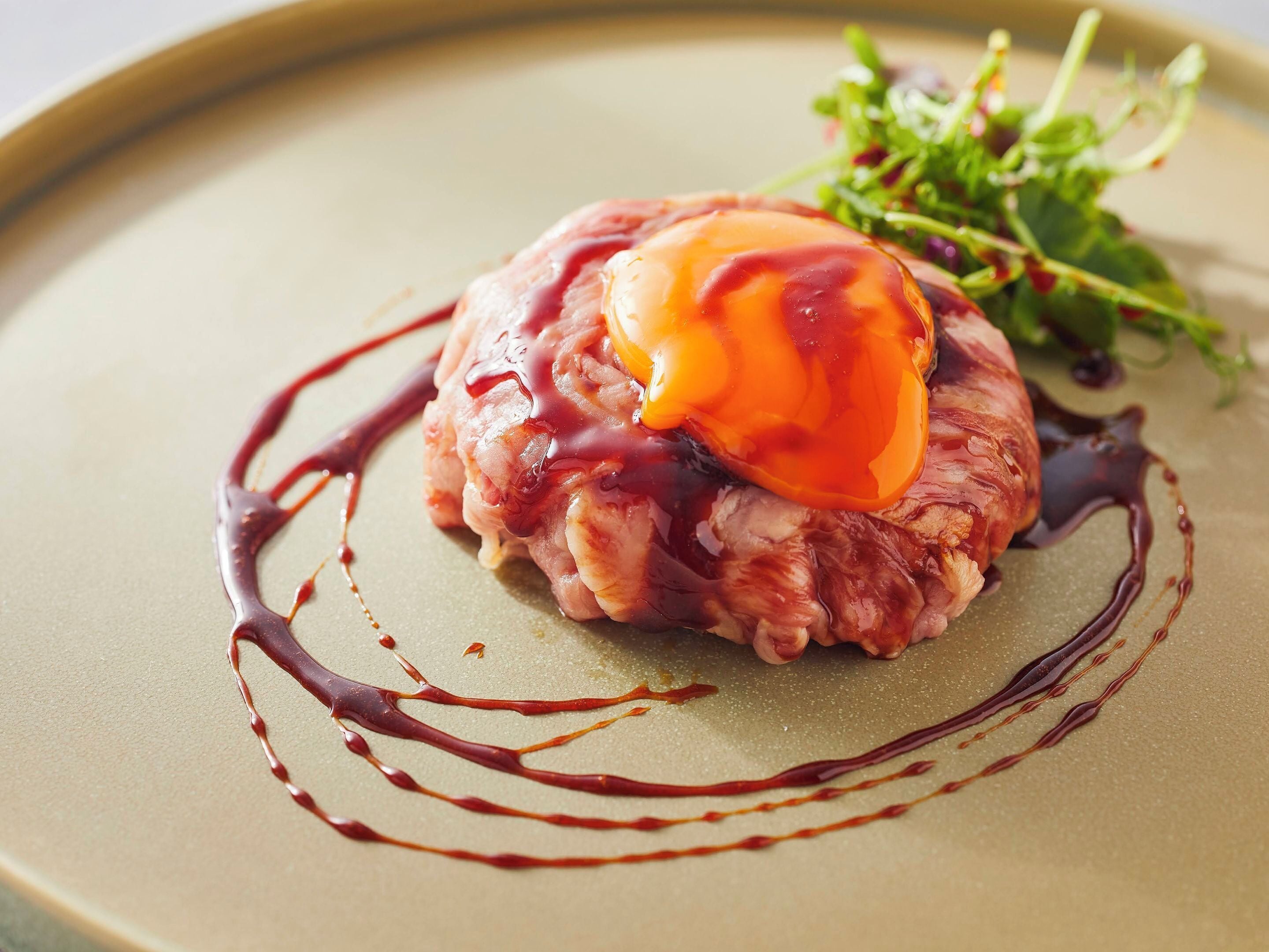 A plate with a meat dish, sauce, and greens.