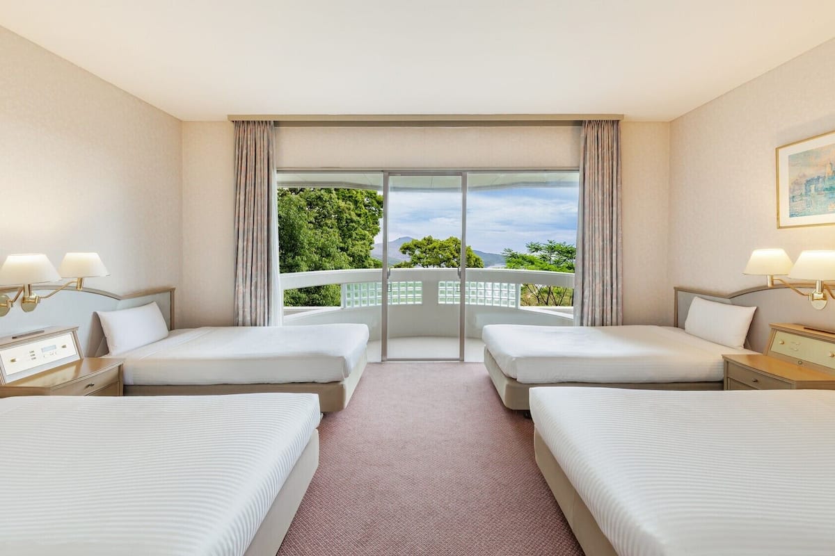 Una habitación de hotel con dos camas, un ventanal con vistas y un cuadro en la pared.