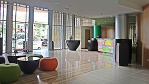 A spacious lobby with large windows, a reception desk, and modern seating areas. - G'Sign Style (Tuban)