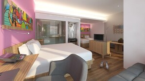A modern hotel room with a large bed, a desk with a laptop, a TV, and a seating area. - G'Sign Style (Tuban)