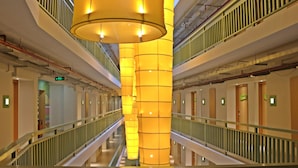 A modern hotel interior with a central column, multiple floors, and a glass railing. - G'Sign Style (Tuban)