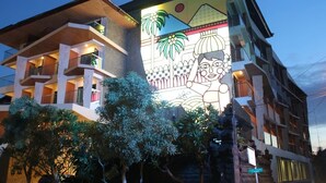 A multi-story building with balconies and a large mural on the facade. - G'Sign Style (Tuban)