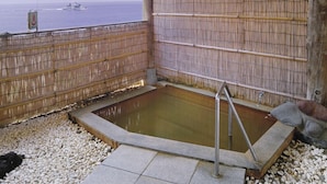 Ett område med ett bubbelbad, omgivet av ett bambustaket, med utsikt över havet och en informationsskylt.