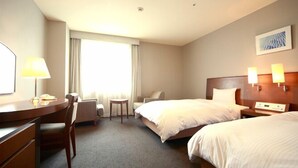 A hotel room with two beds, a desk, a chair, a small table, and a window with curtains. - Hotel Brillante Musashino (Saitama)
