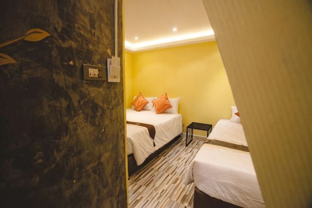 A hotel room with two beds, a marble wall, and a yellow wall.