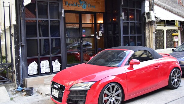 A red convertible parked in front of a building with a sign reading "Double Five."