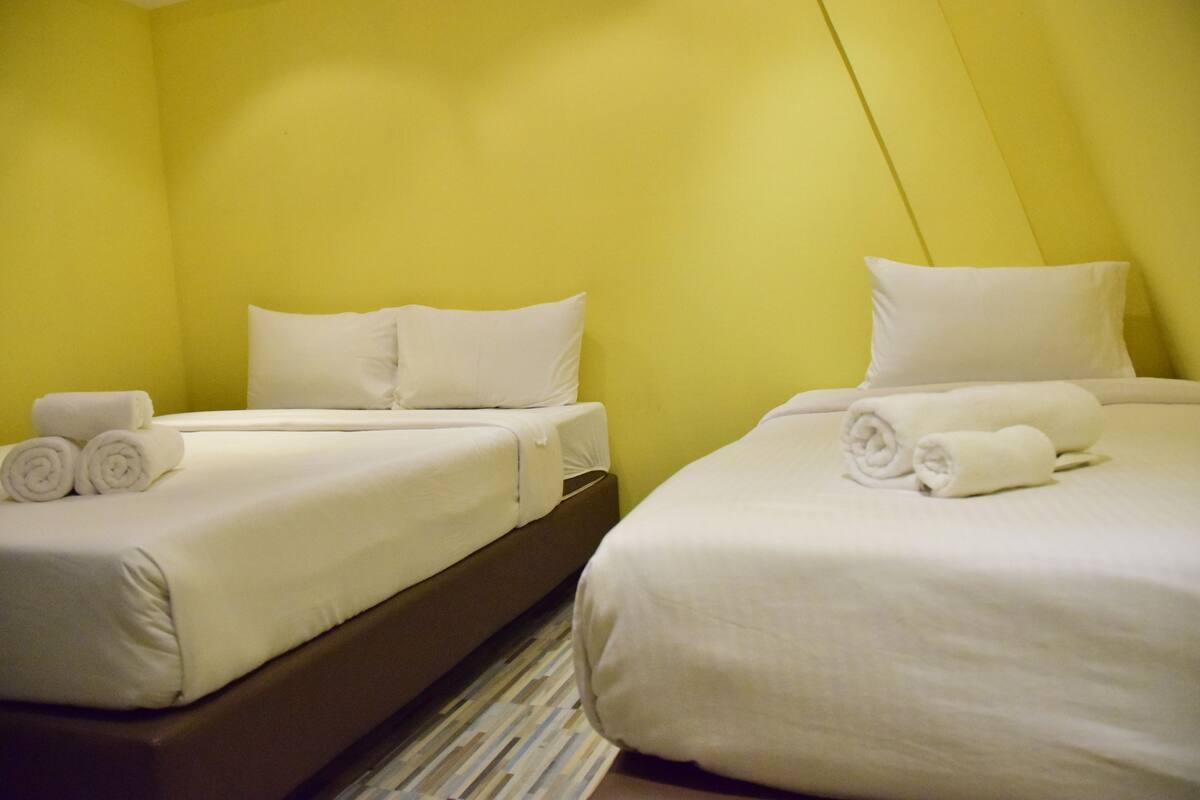 Two single beds with white linens and pillows, a striped floor, and yellow walls.