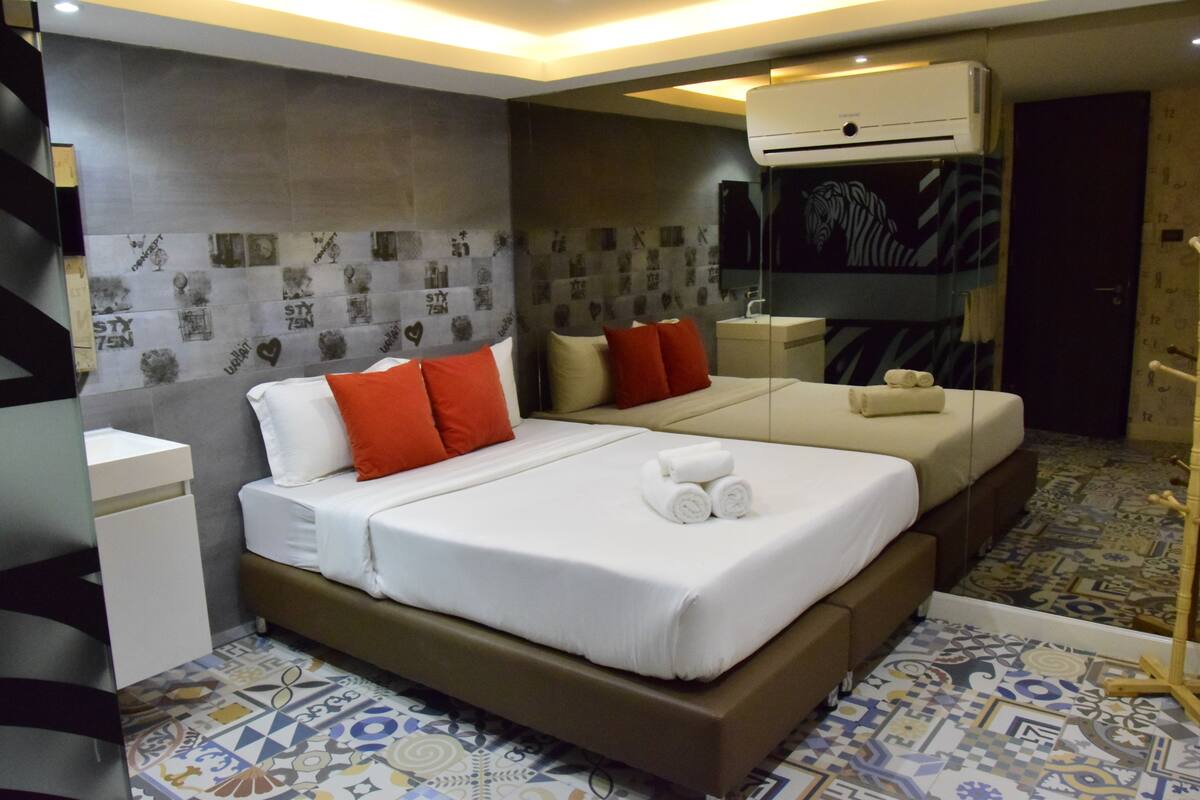 A hotel room with a large bed, two bedside tables, a mirror, and a patterned floor.