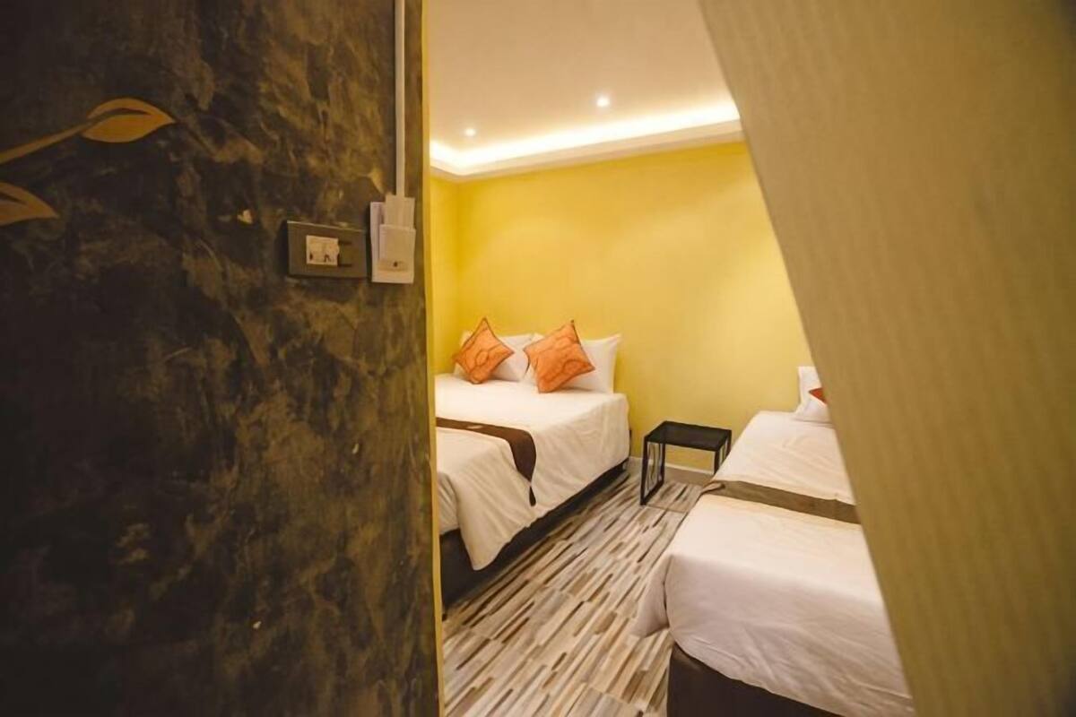 A hotel room with two beds, a marble wall, and a yellow wall.
