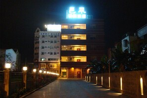 Un hotel con un letrero llamativo, varios pisos y una entrada bien iluminada.