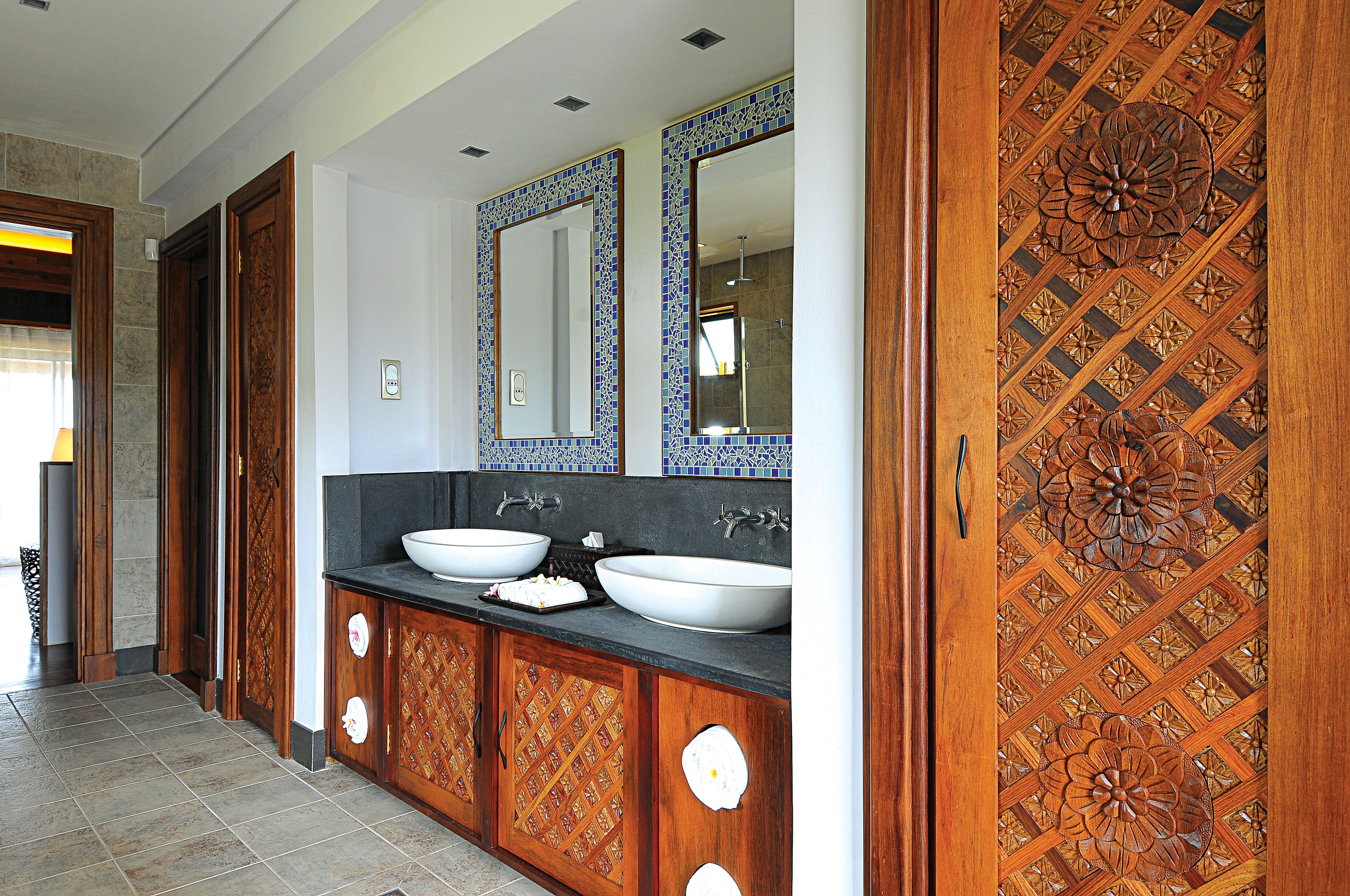 A bathroom with two sinks, wooden cabinets, and a decorative ceiling.