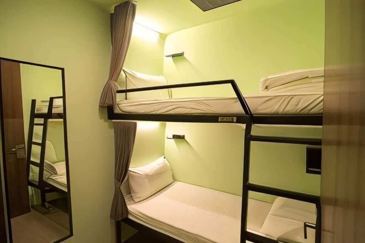 A bunk bed room with a ladder, a mirror, and a curtain.