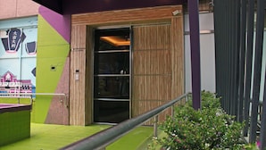 Une entrée d’immeuble avec une porte en bois, une rampe verte et une rambarde en métal.