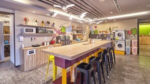Une cuisine moderne dotée d’un long comptoir, de tabourets de bar et de divers appareils électroménagers, comme un four à micro-ondes et un lave-linge.
