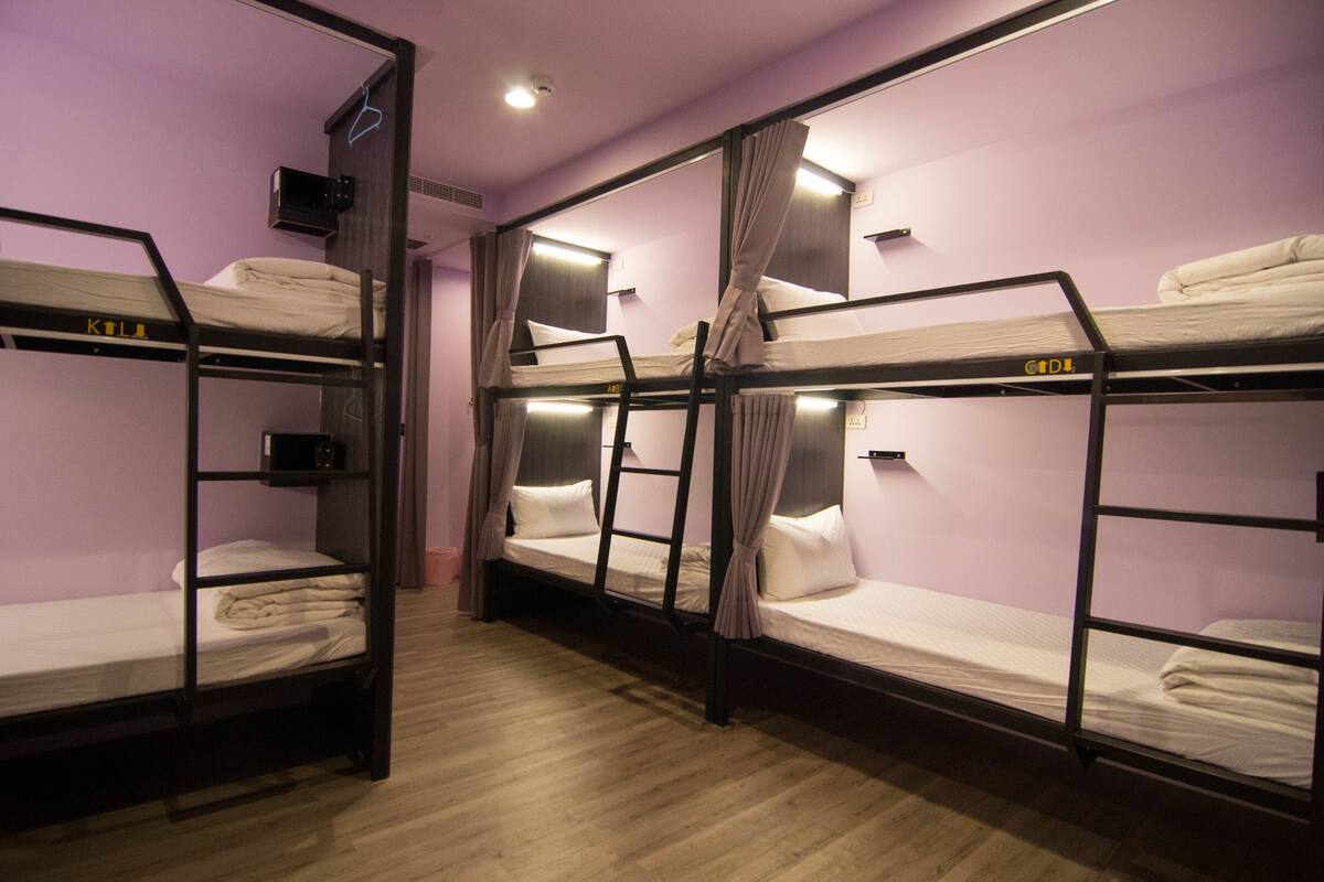 A room with bunk beds, wooden flooring, and a purple wall.