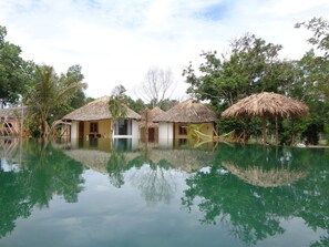 A pool with thatched-roof huts and palm trees.