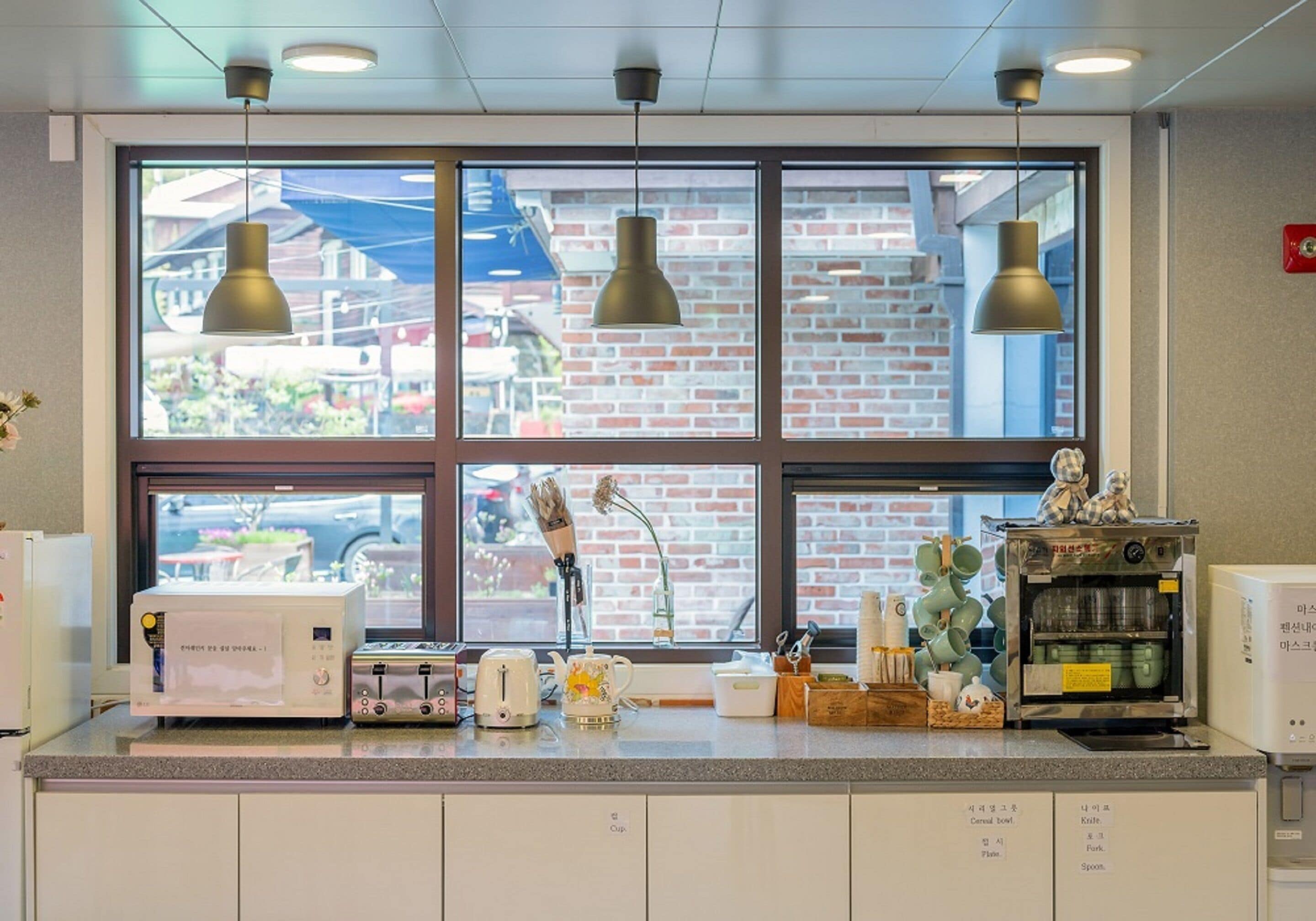 Una cocina con un ventanal amplio, microondas, tostadora, hervidor y cafetera.