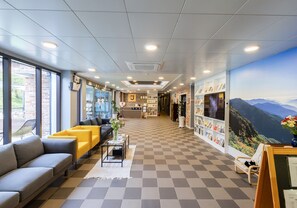 A hotel lobby with a checkered floor, seating areas, a reception desk, and a large mural. - Stay Jirisan Parkview (Gurye)
