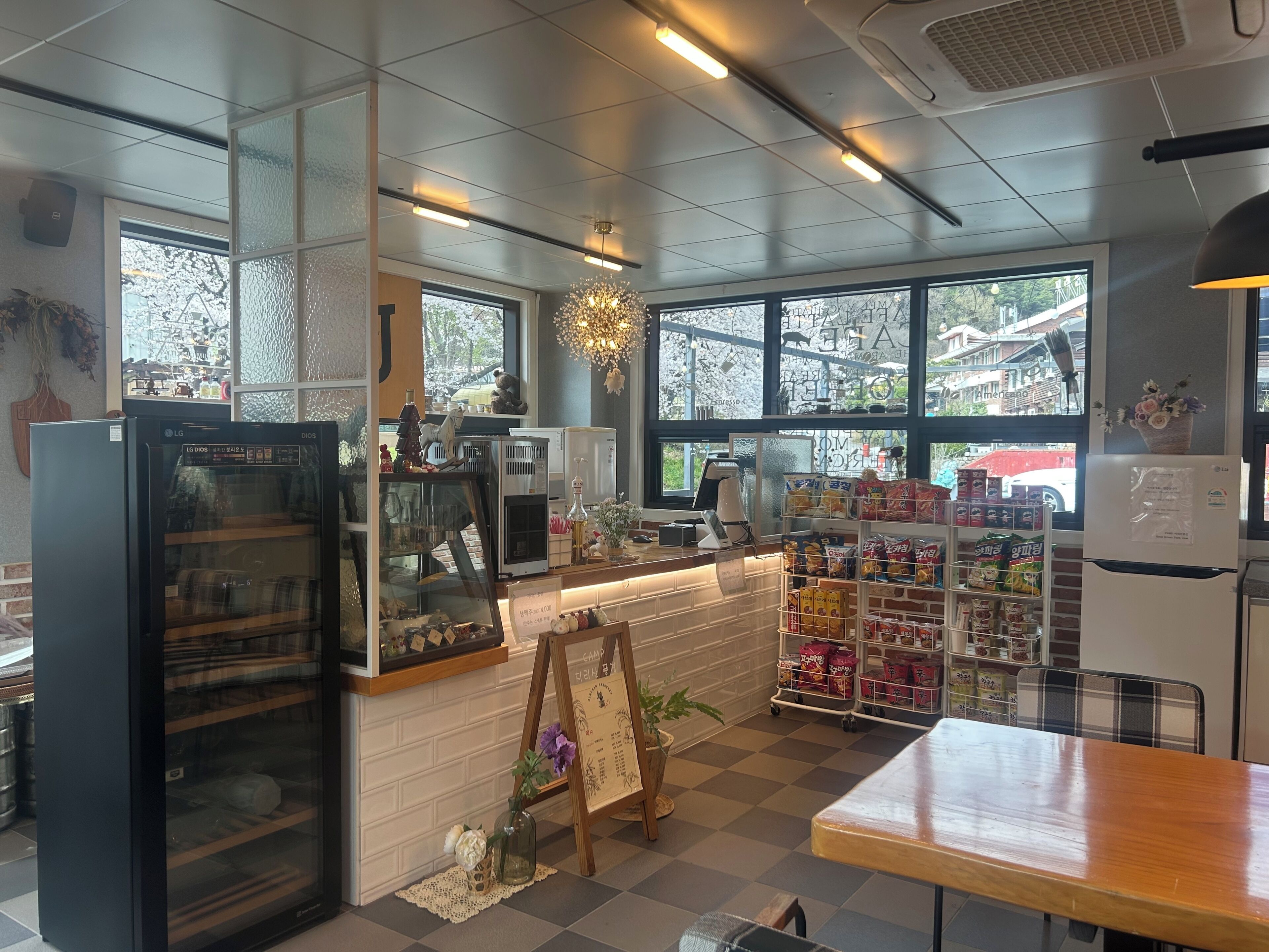 Interior de una cafetería con mostrador, zona de estar y amplios ventanales.